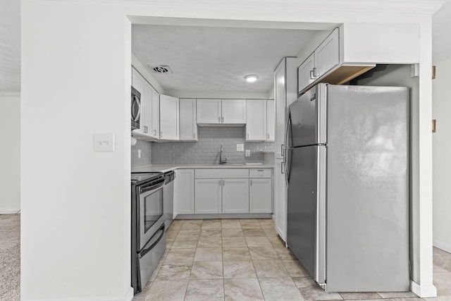 kitchen featuring tasteful backsplash, light countertops, visible vents, appliances with stainless steel finishes, and a sink