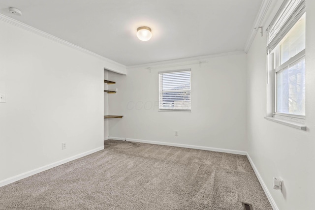 spare room with carpet, visible vents, crown molding, and baseboards