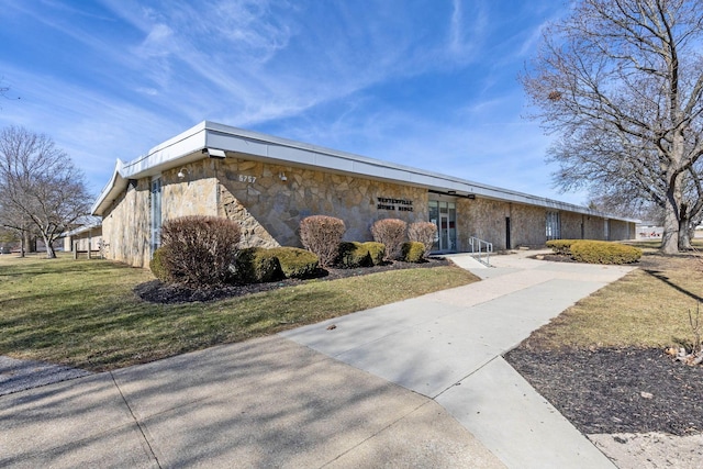 mid-century home featuring a front yard and stone siding