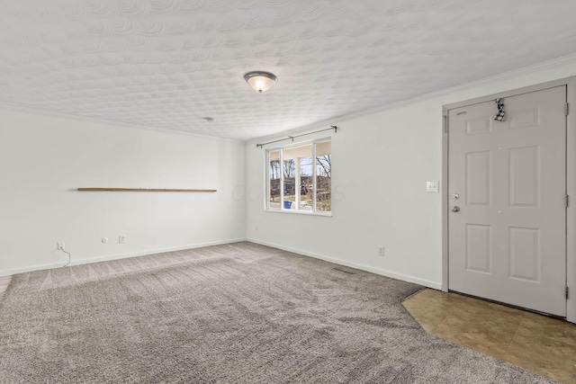 carpeted empty room featuring baseboards, a textured ceiling, and ornamental molding