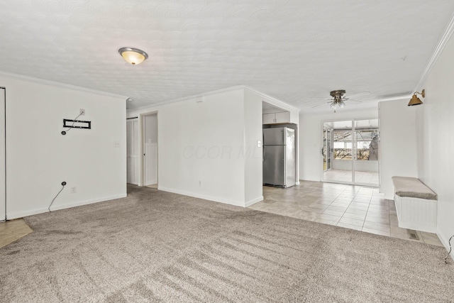 tiled spare room with ceiling fan, a textured ceiling, carpet flooring, baseboards, and crown molding