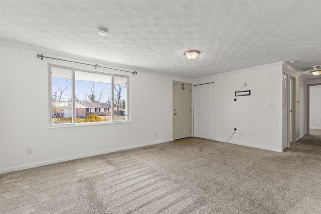 carpeted spare room featuring baseboards, a textured ceiling, visible vents, and crown molding