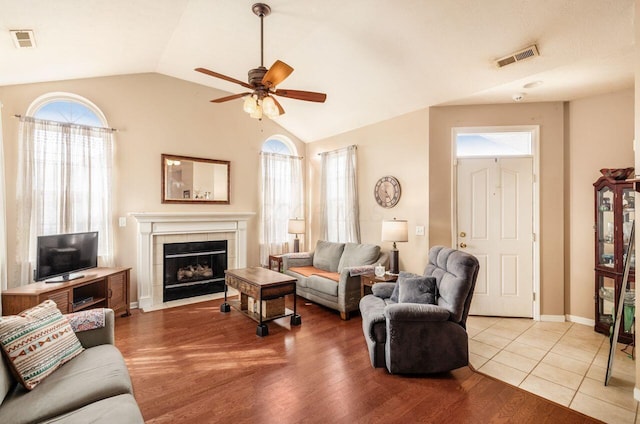 living area featuring lofted ceiling, visible vents, a fireplace, and light wood-style flooring