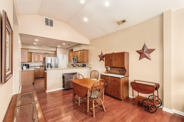 dining space with lofted ceiling, wood finished floors, visible vents, and baseboards