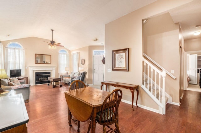 dining room featuring stairs, a fireplace, vaulted ceiling, and wood finished floors