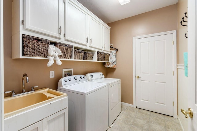 clothes washing area with cabinet space, baseboards, a sink, and washing machine and clothes dryer