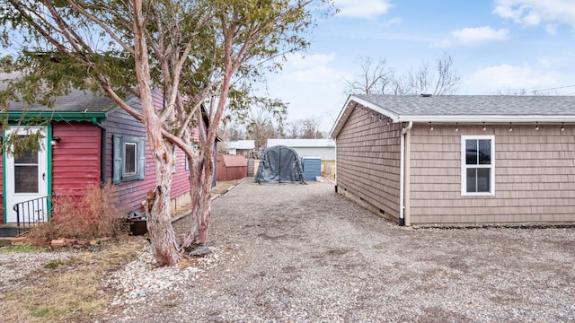 view of property exterior featuring driveway and a shingled roof