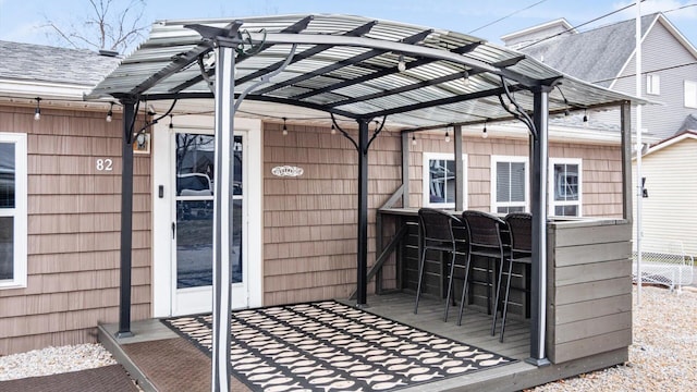 exterior space featuring a shingled roof, fence, and outdoor dry bar