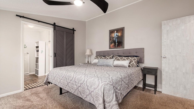 bedroom with a textured ceiling, a barn door, carpet, and a ceiling fan