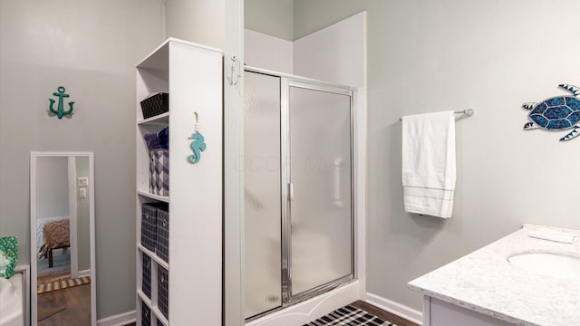 bathroom featuring a shower stall, baseboards, wood finished floors, and vanity