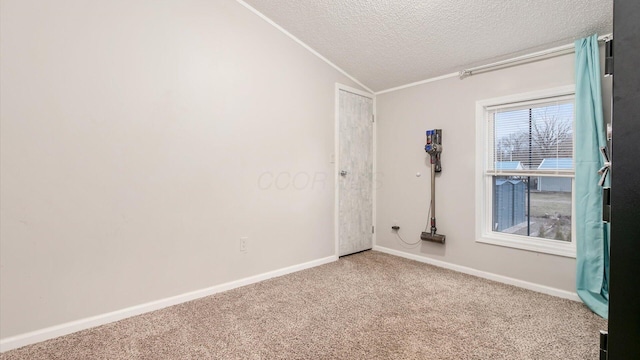 carpeted spare room with ornamental molding, vaulted ceiling, a textured ceiling, and baseboards