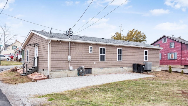 back of house with entry steps, driveway, crawl space, and roof with shingles