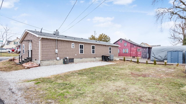 back of house with entry steps, crawl space, driveway, and a yard