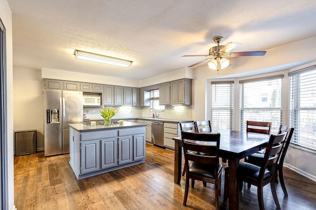 kitchen with stainless steel appliances, a sink, a healthy amount of sunlight, gray cabinets, and dark countertops