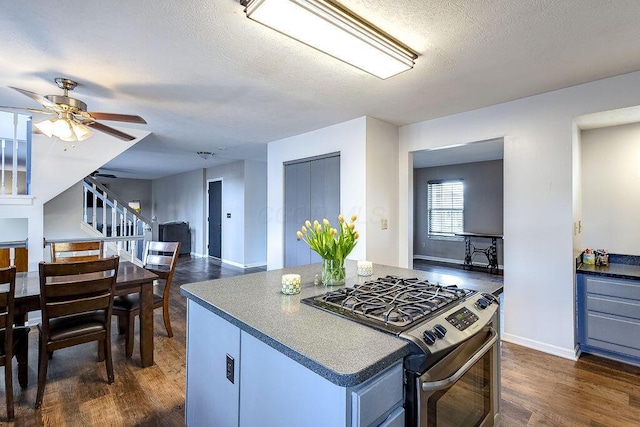 kitchen featuring dark wood-style flooring, a kitchen island, ceiling fan, a textured ceiling, and gas range