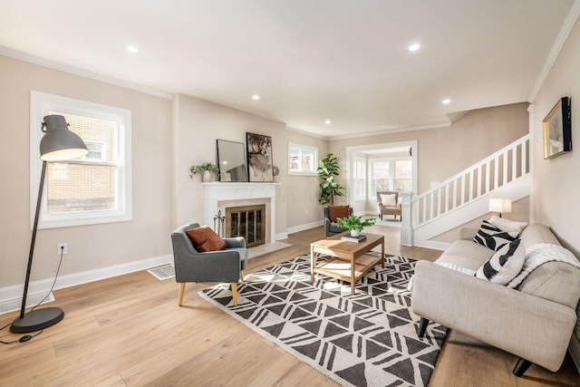 living area with light wood-style floors, visible vents, and crown molding