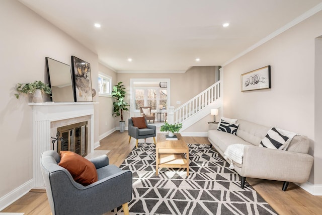 living room with light wood finished floors, stairway, a tiled fireplace, and baseboards