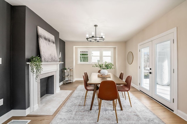 dining area featuring light wood-type flooring, french doors, baseboards, and an inviting chandelier