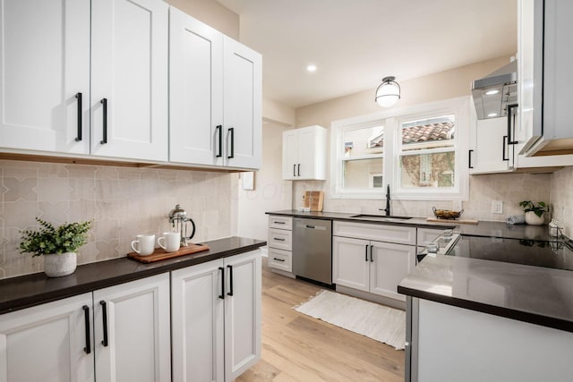 kitchen featuring a sink, white cabinets, light wood-style floors, dishwasher, and dark countertops