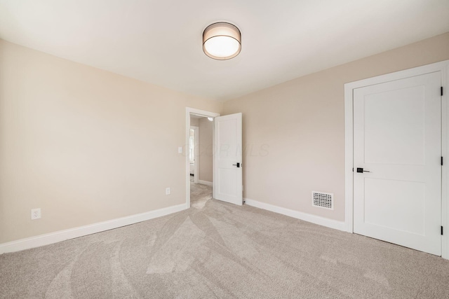 spare room featuring light carpet, baseboards, and visible vents