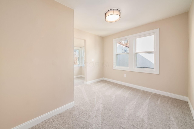 carpeted empty room featuring baseboards