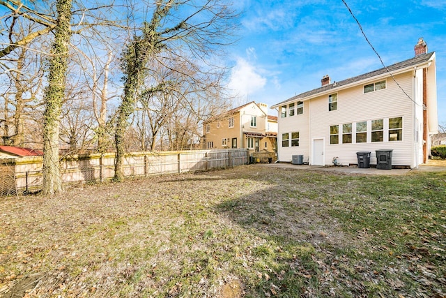 rear view of property with central AC, a fenced backyard, and a chimney