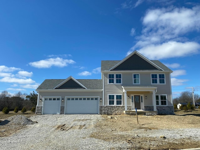 craftsman-style house with a garage, stone siding, and gravel driveway