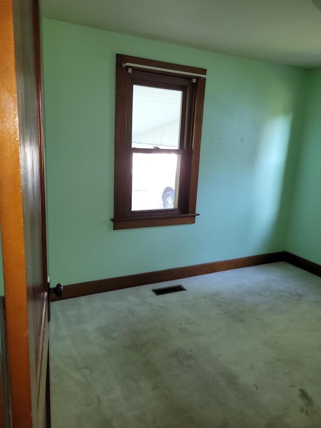 spare room with carpet floors, visible vents, and baseboards