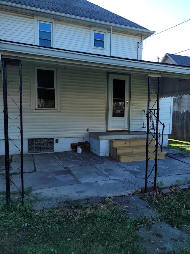 exterior space featuring covered porch, fence, and roof with shingles