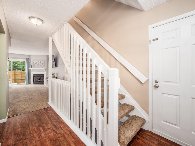 5610 Barney Ln Unit 41F, Columbus, OH 43235 - staircase with a textured ceiling, a fireplace, wood finished floors, and baseboards