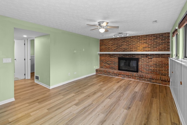 unfurnished living room with light wood-type flooring, a fireplace, visible vents, and baseboards