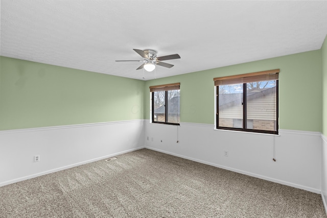 carpeted spare room featuring visible vents, ceiling fan, and baseboards