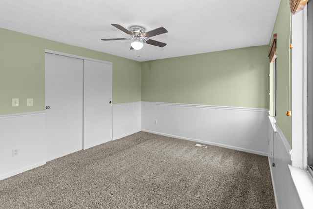 unfurnished bedroom with baseboards, carpet, a ceiling fan, and a closet