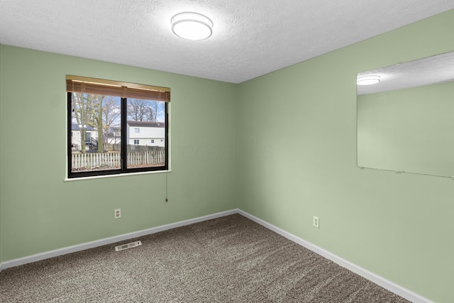 carpeted empty room featuring visible vents, a textured ceiling, and baseboards