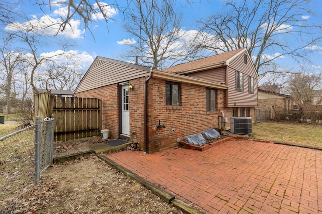 view of side of property featuring a patio area, brick siding, a fenced backyard, and central AC unit