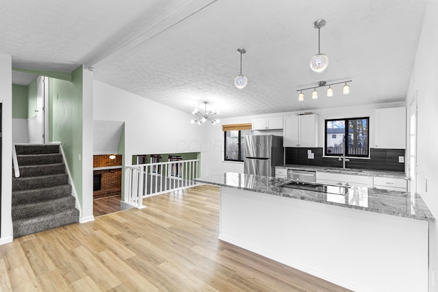 kitchen featuring vaulted ceiling with beams, a textured ceiling, stainless steel appliances, white cabinetry, and light wood-style floors