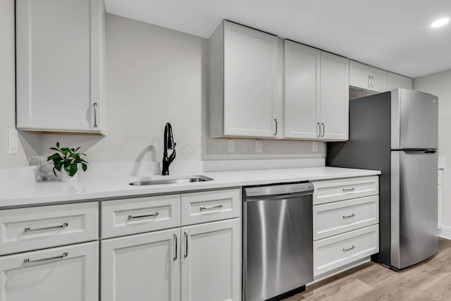 kitchen featuring light wood-style flooring, stainless steel appliances, a sink, and light countertops