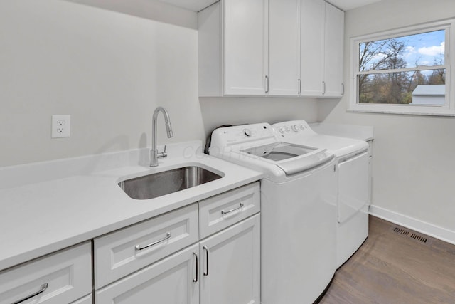 laundry area with cabinet space, visible vents, baseboards, washer and dryer, and a sink