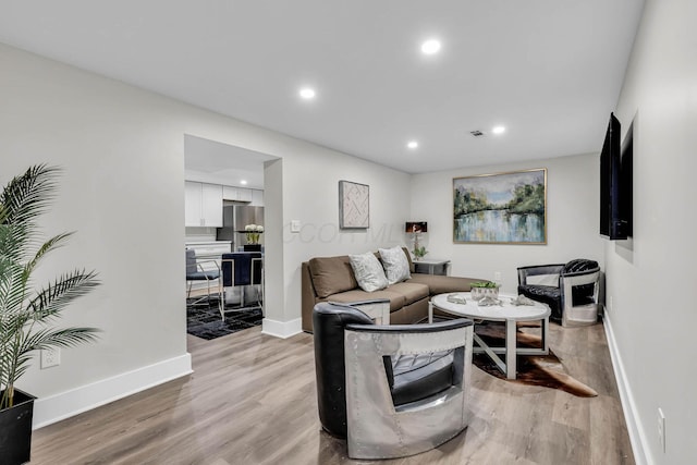 living area featuring light wood-type flooring, baseboards, and recessed lighting