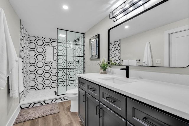 bathroom featuring recessed lighting, toilet, vanity, a shower stall, and wood finished floors