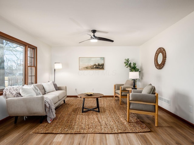 living room with baseboards, visible vents, ceiling fan, and wood finished floors