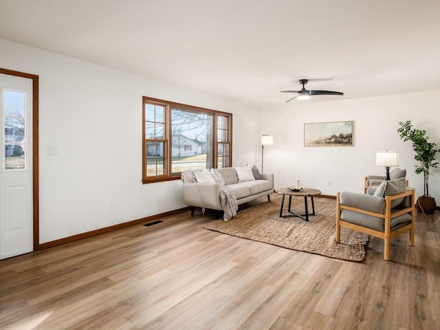 living area with light wood-style flooring, a ceiling fan, visible vents, and baseboards