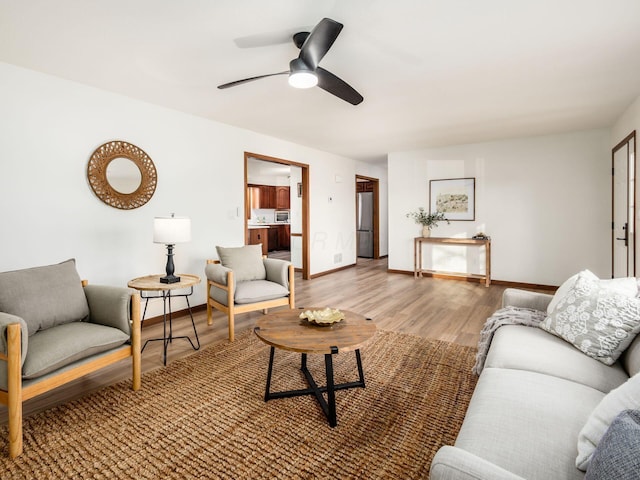 living area featuring a ceiling fan, baseboards, and wood finished floors