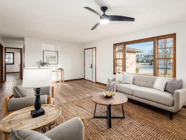 living area with ceiling fan, light wood-type flooring, and baseboards