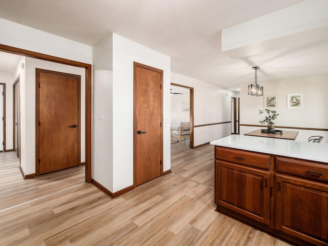 kitchen with hanging light fixtures, light wood-style floors, baseboards, and light countertops