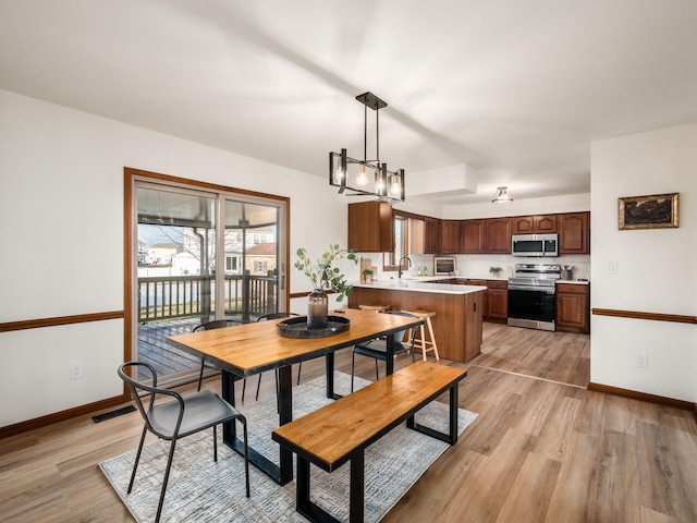 dining space with light wood-type flooring, visible vents, and baseboards