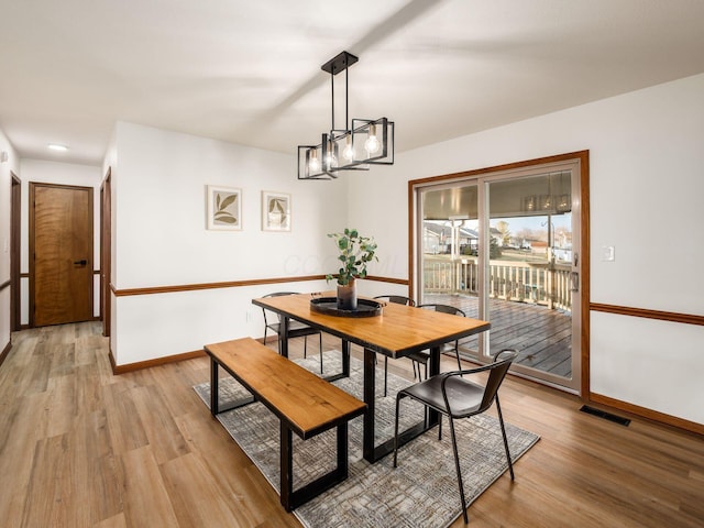 dining space with light wood-style floors, visible vents, and baseboards