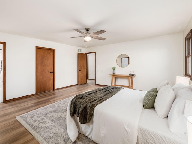 bedroom featuring a ceiling fan, baseboards, visible vents, and wood finished floors