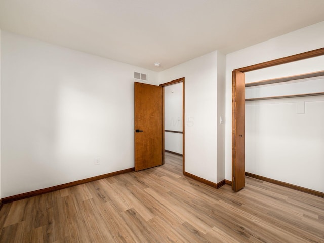 unfurnished bedroom featuring baseboards, a closet, visible vents, and light wood-style floors