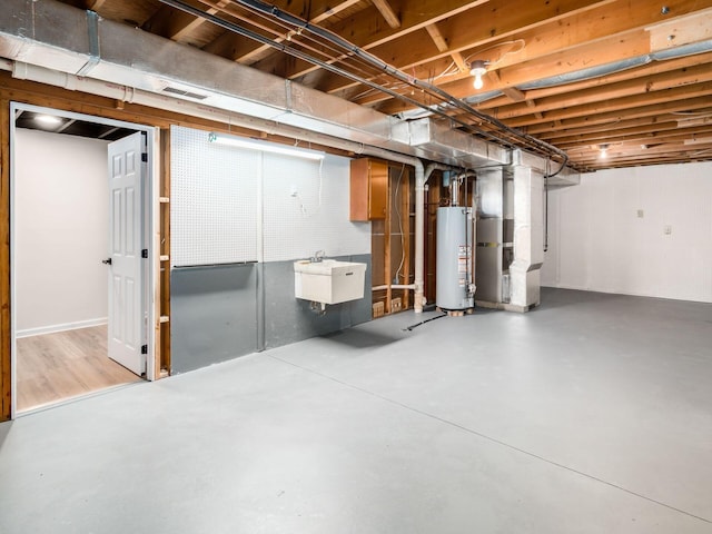 unfinished below grade area featuring heating unit, water heater, visible vents, and a sink